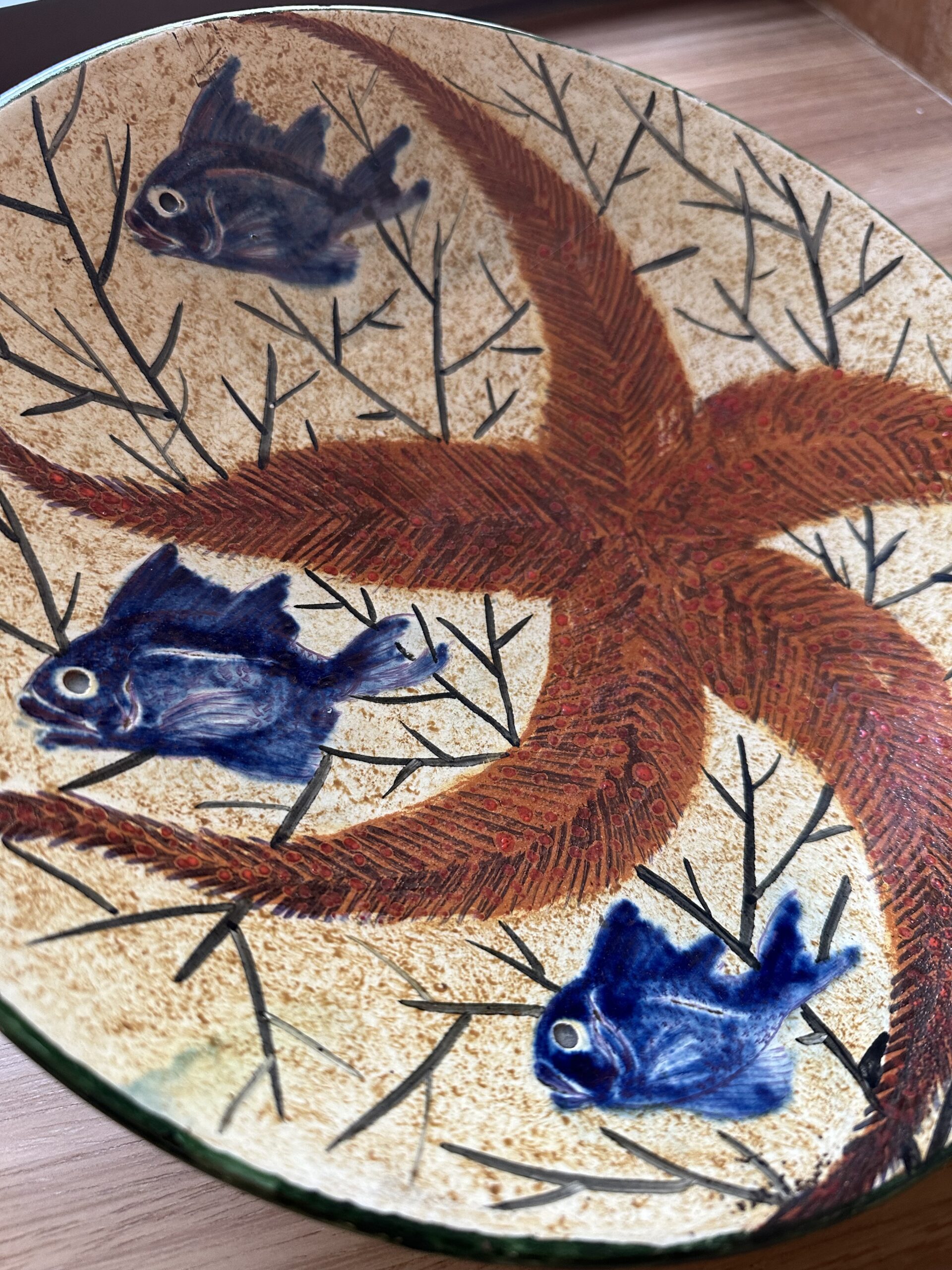 Assiette en céramique artisanale de Diaz Costa ornée de trois poissons bleus et d’une étoile de mer.