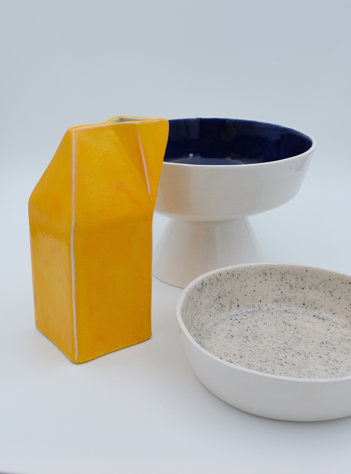 Vaisselle Pop Art de la collection Package, atelier Romain Roche céramique à Montpellier - avec pichet jaune vif, coupe bleu « nu » et bol moucheté.